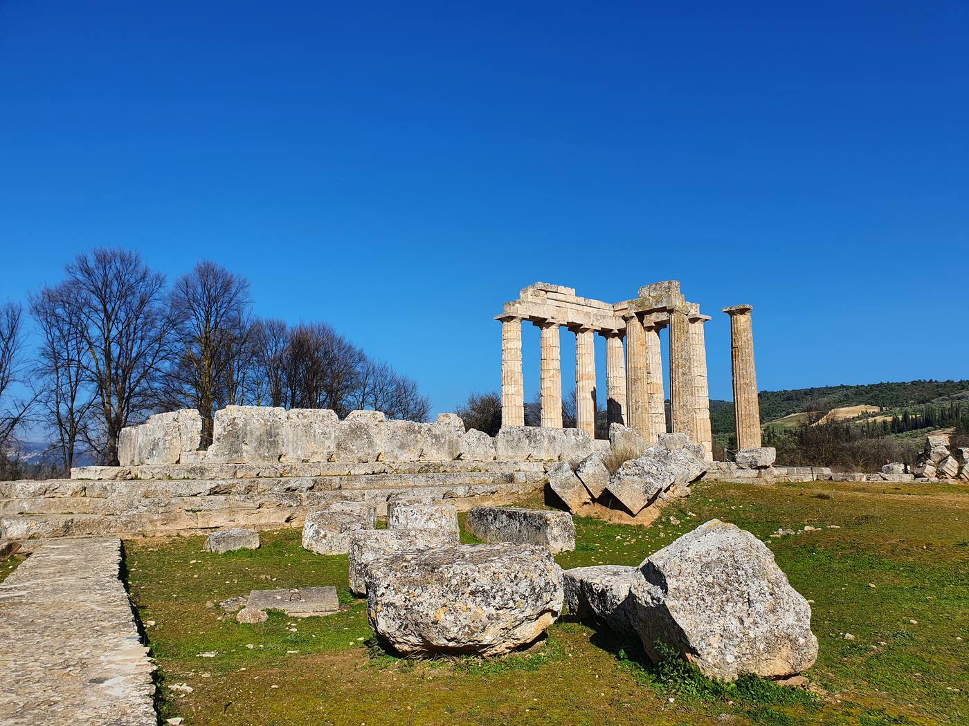 The Temple of Zeus at Ancient Nemea, its tall Doric columns rising from the archaeological site with hills in the background