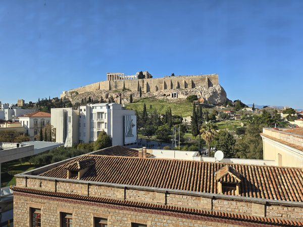 A rooftop view across Plaka's terracotta roofs to the Acropolis and Parthenon beyond
