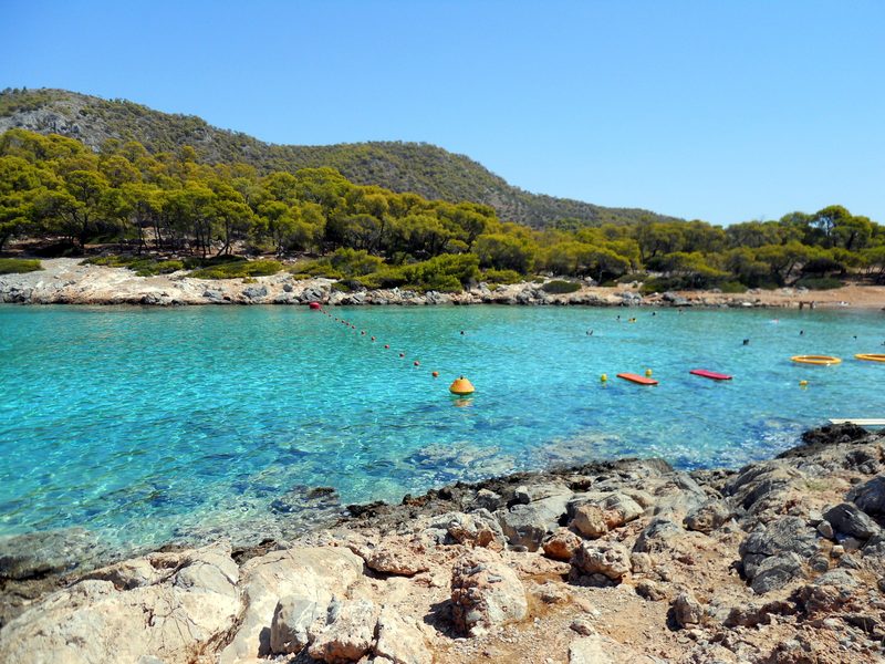 The calm turquoise bay at Aponisos on Agistri island, with pine-covered hillsides reaching down to the water